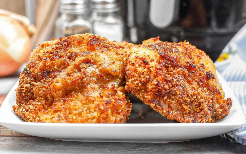 Crispy panko-coated chicken thighs served on a white plate with a side garnish.