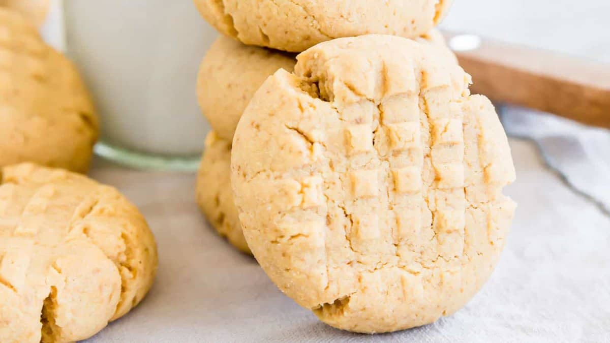 Gluten free peanut butter cookie leaning against a stack of cookies in the background.