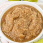 A white bowl filled with chunky, brown applesauce, with a soft texture and visible fruit pieces.