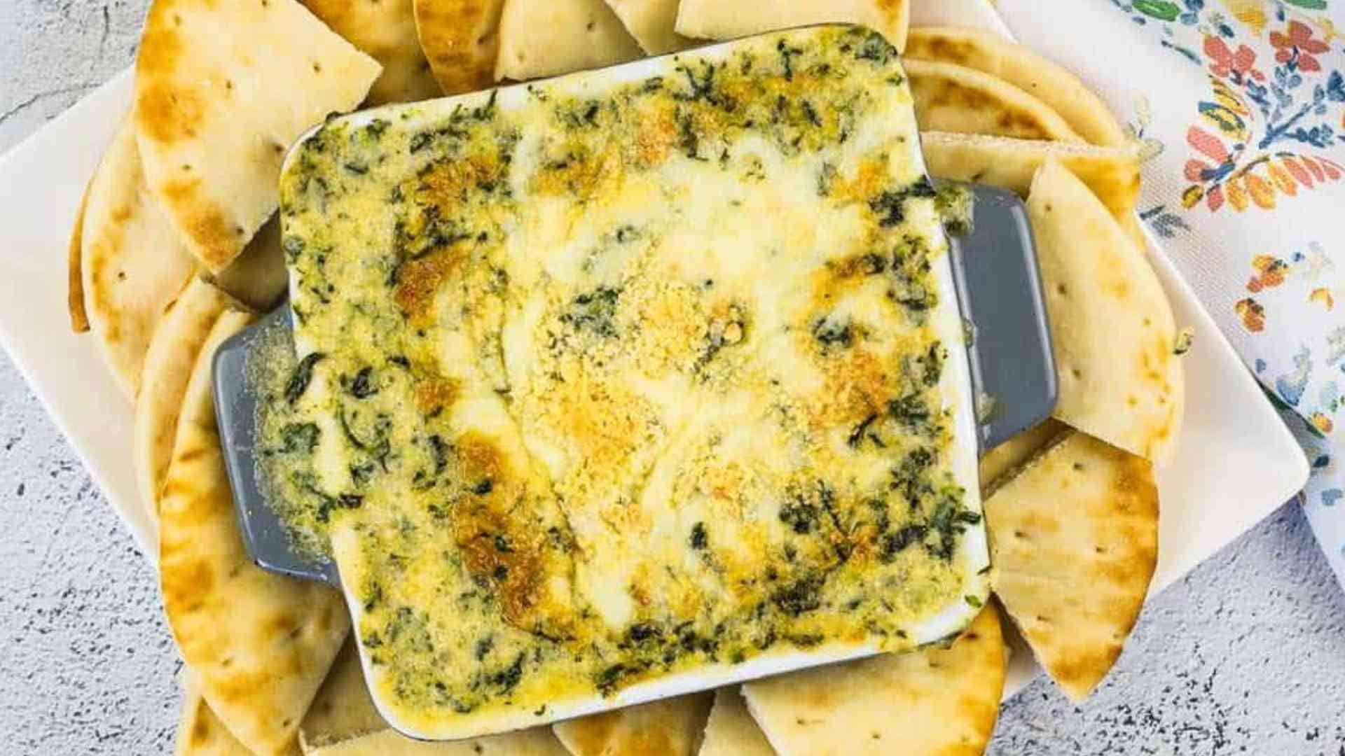 Spinach & Brie Dip in a casserole dish surrounded by pita wedges.