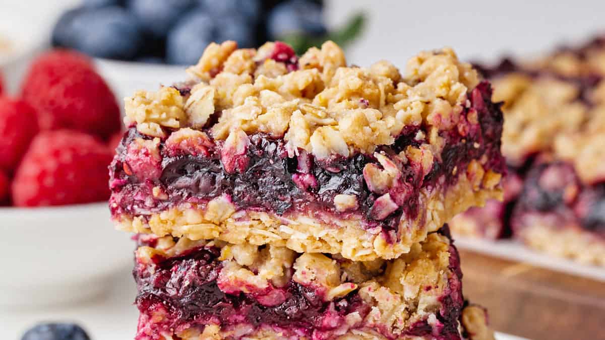 Stack of berry bars with berries in the background.