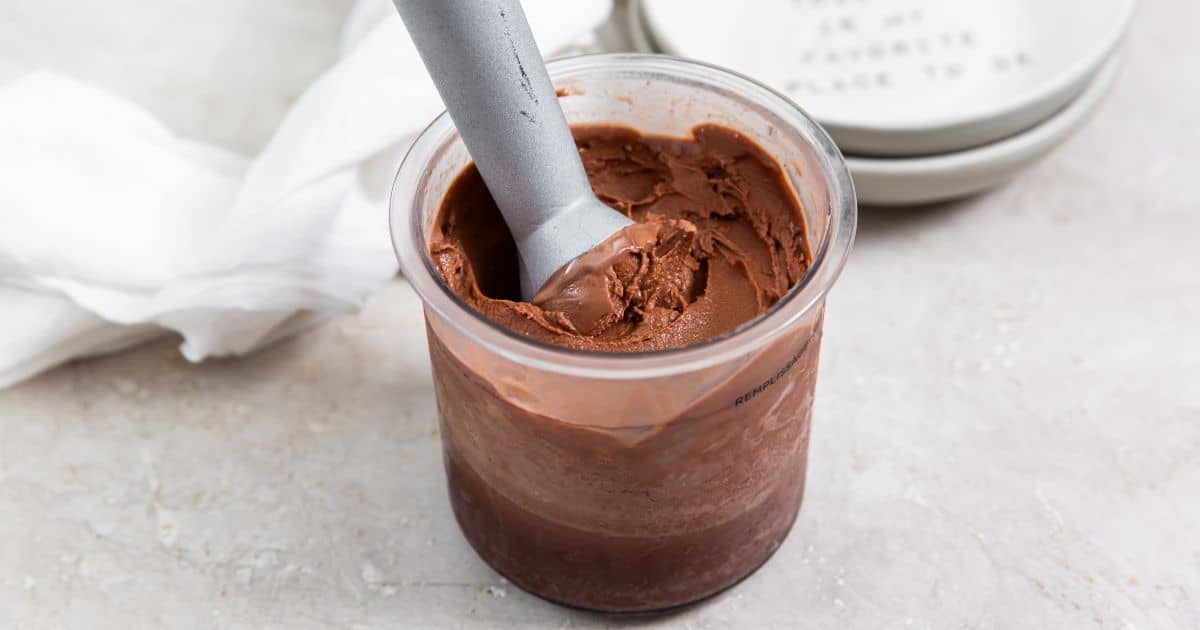 Chocolate Dairy Free Keto Ice Cream Ninja CREAMi in a glass jar with an ice cream scoop.
