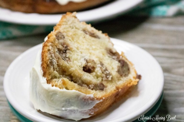 A slice of bundt cake with visible cinnamon swirls and a layer of white icing on the side, served on a white plate.