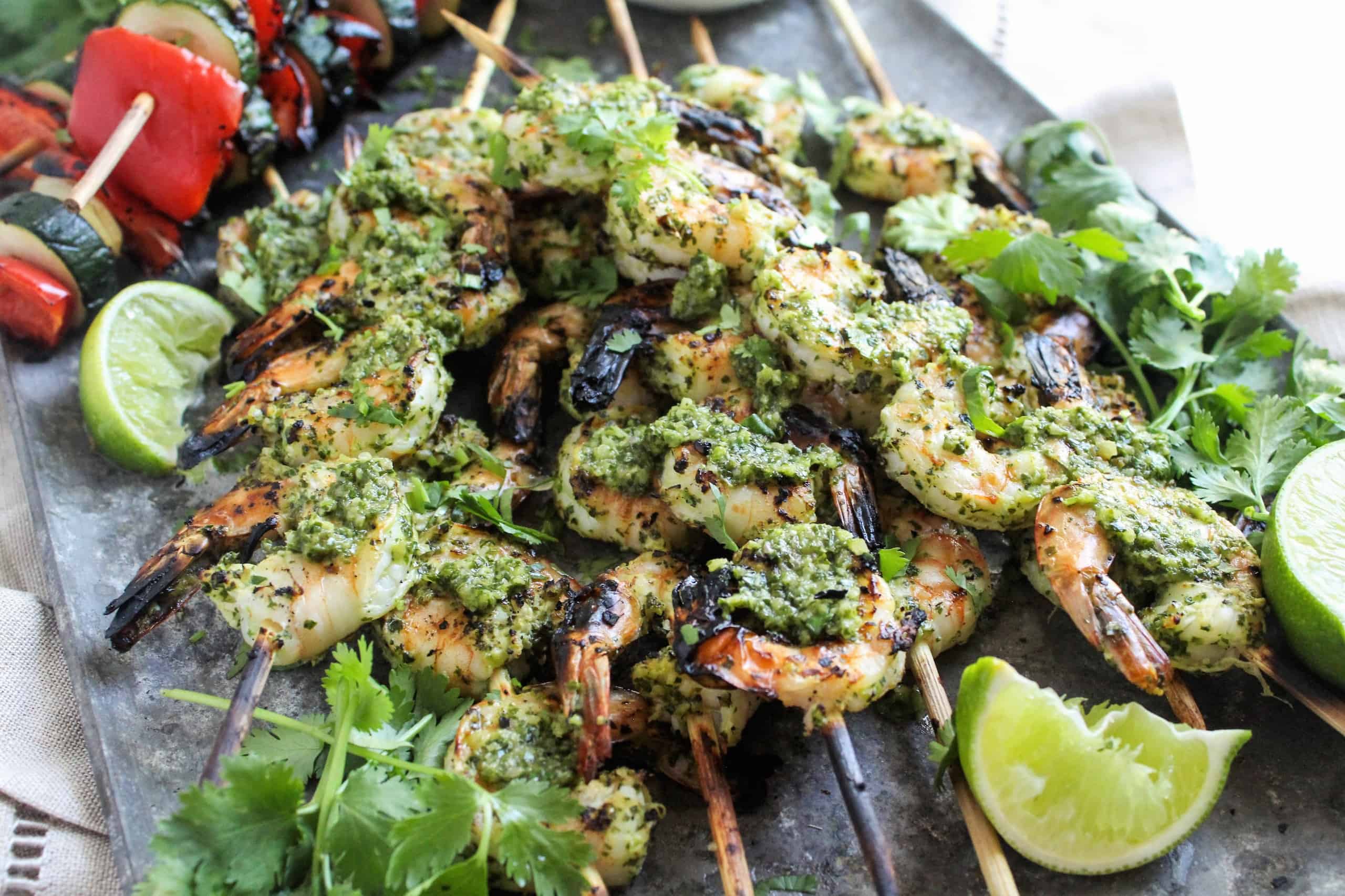 Shrimp skewers with chimichurri sauce drizzled on top.