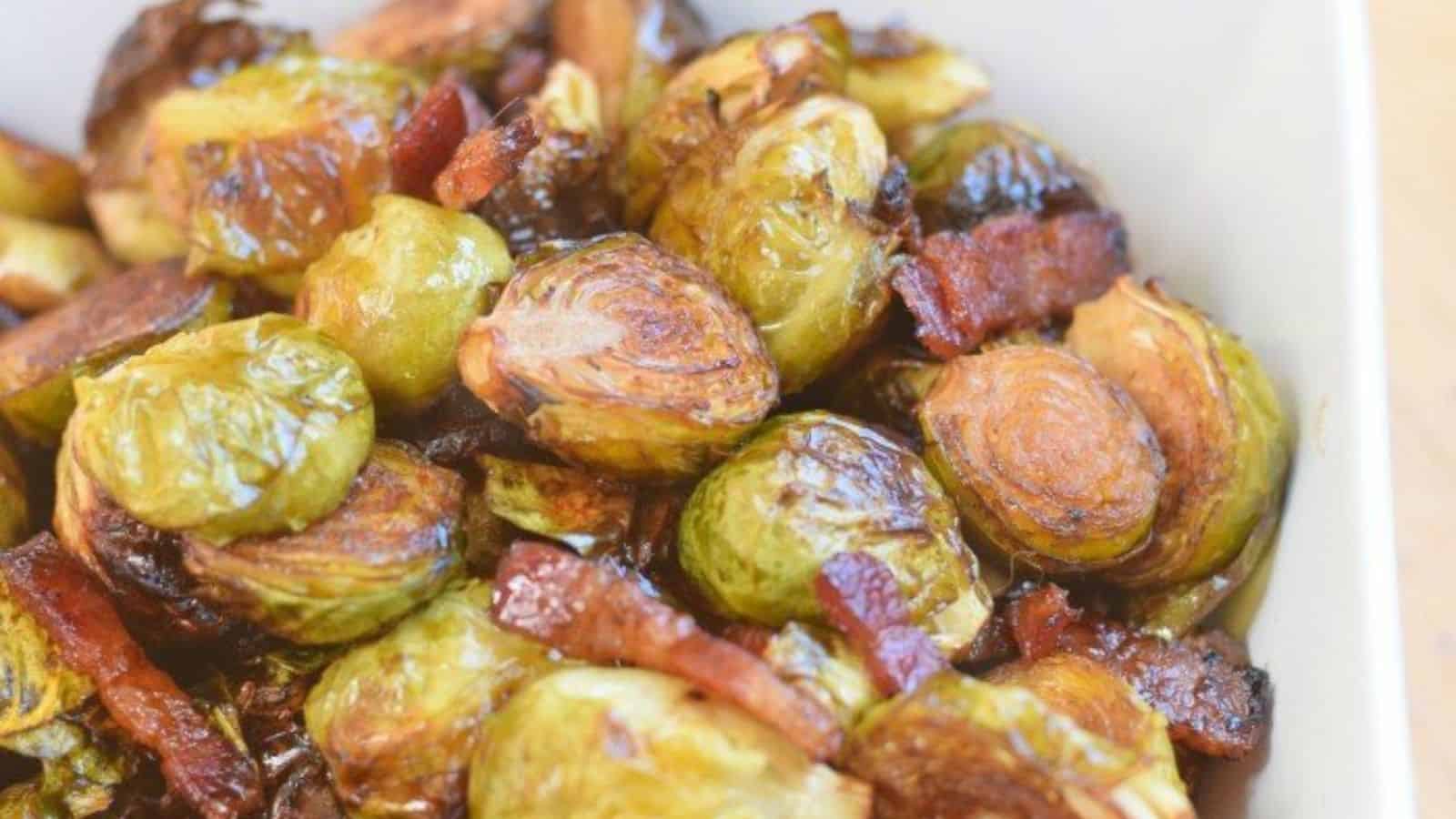 Roasted Brussels sprouts mixed with crispy bacon pieces in a white dish.