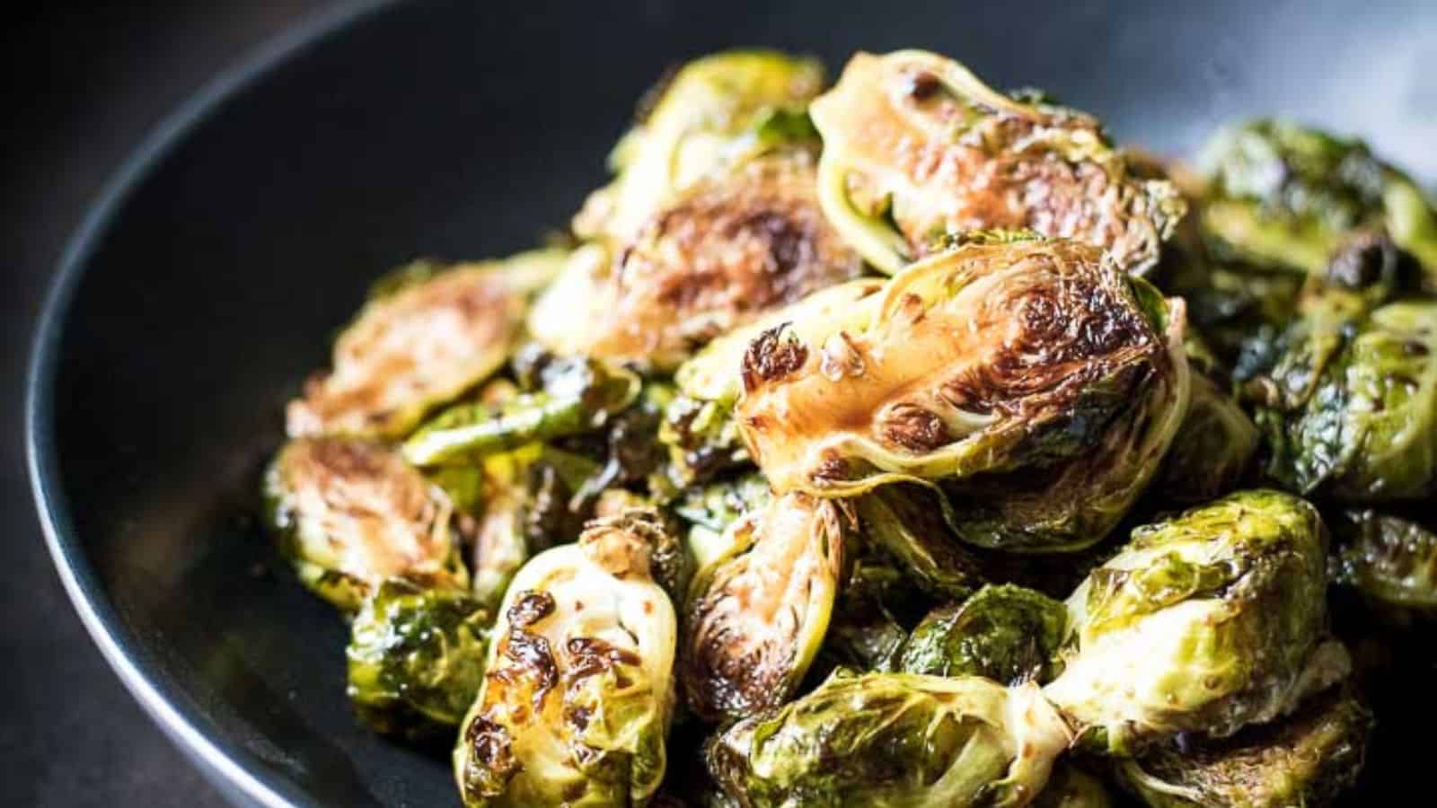 A close-up of roasted Brussels sprouts served in a dark bowl.