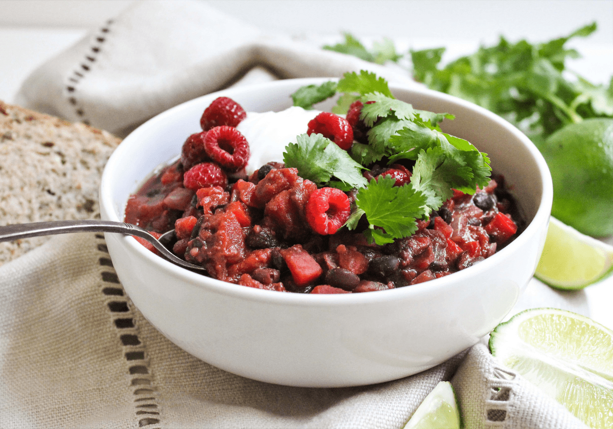 A white bowl filled with raspberry black bean chili topped with cilantro and Greek yogurt.