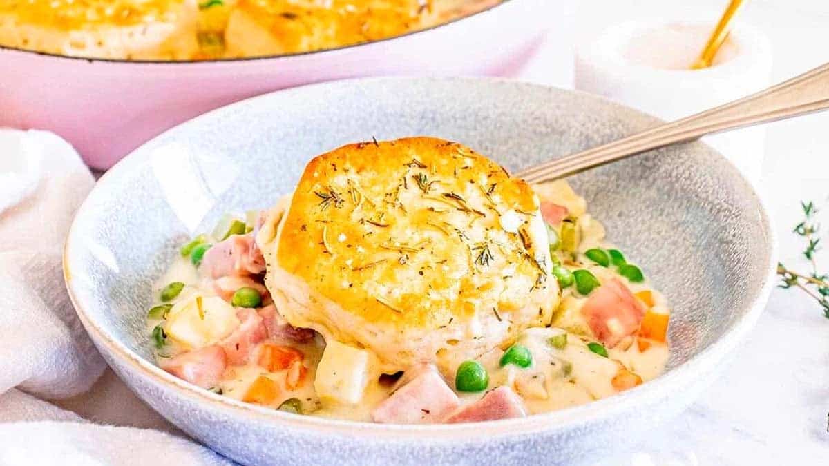 A bowl with pot pie with a biscuit on top.