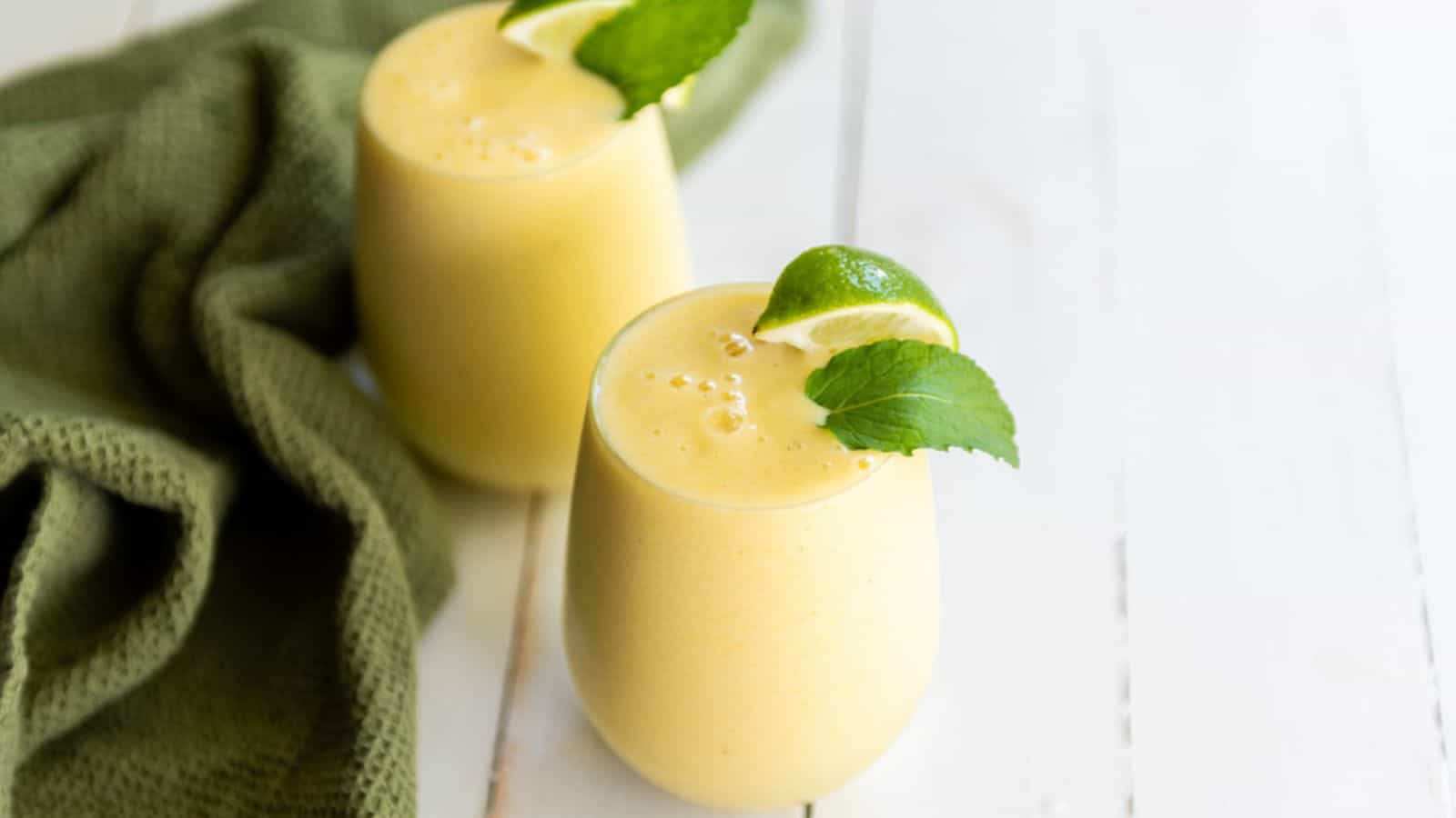 Two glasses with tropical smoothie and limes.