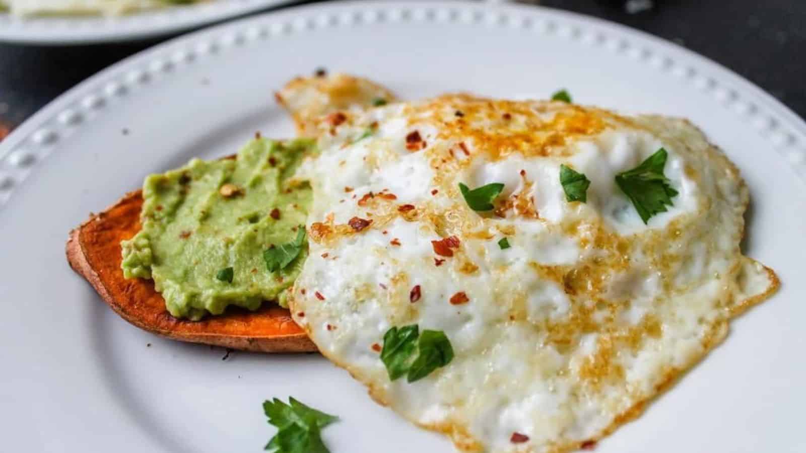 A plate of sweet potato toast topped with avccado and egg.
