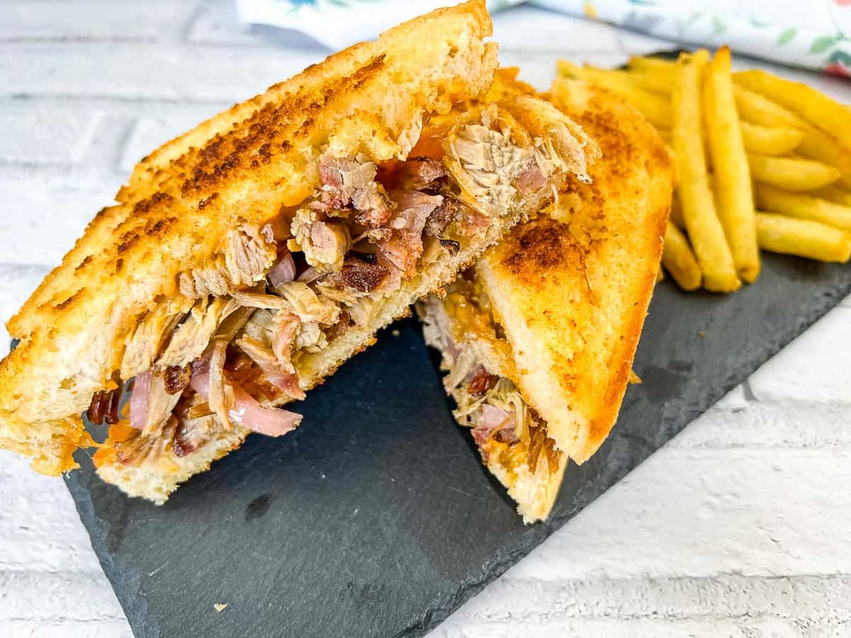 A pulled pork grilled cheese sandwich on a slate plate.