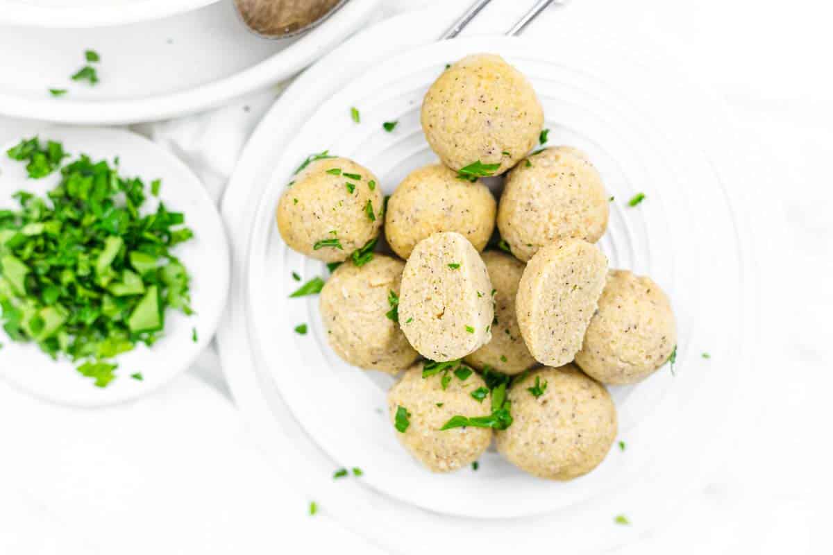 A plate of cooked dumpling balls garnished with chopped parsley.