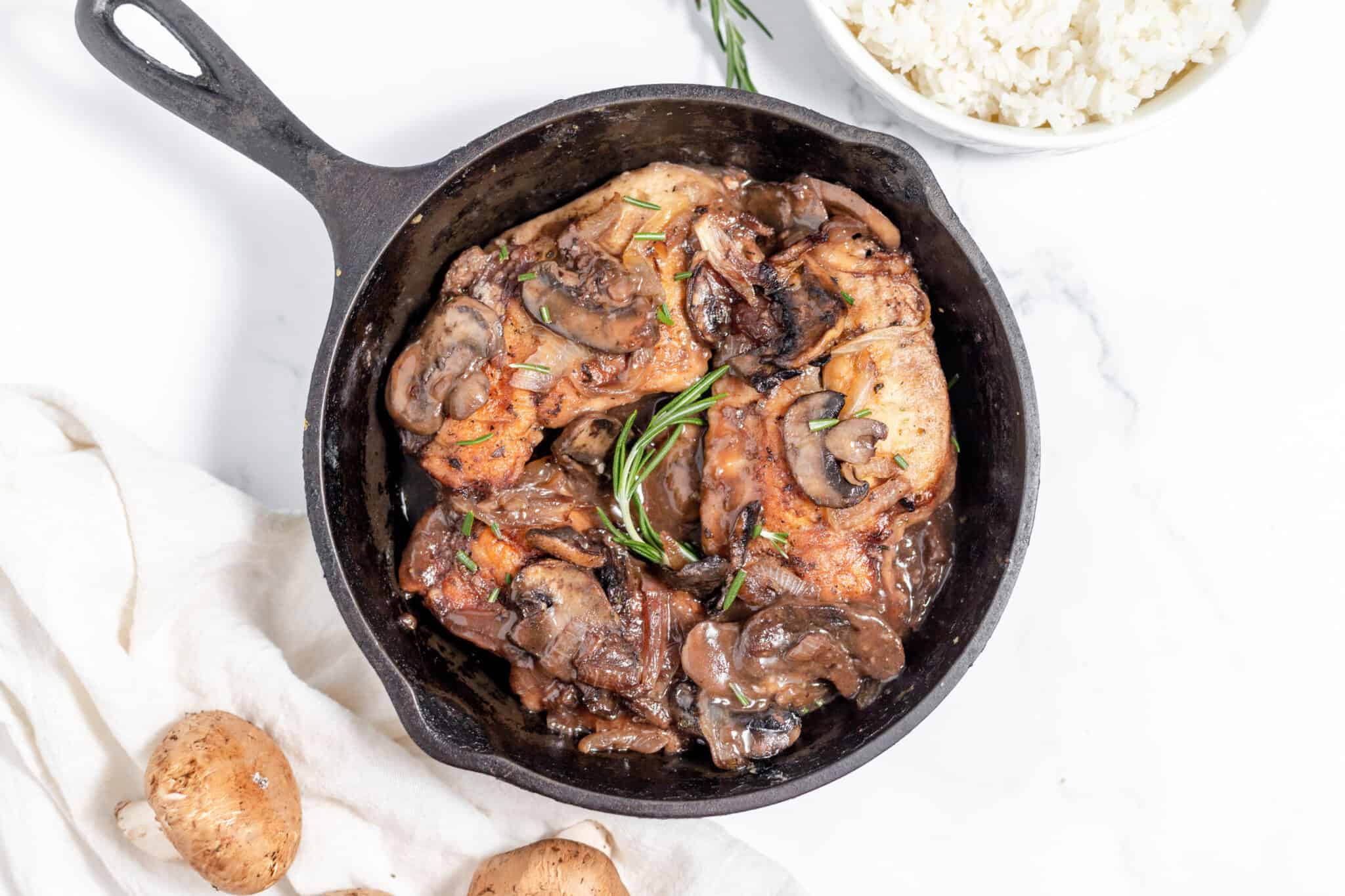 Roasted chicken with mushrooms and potatoes in a cast iron skillet.