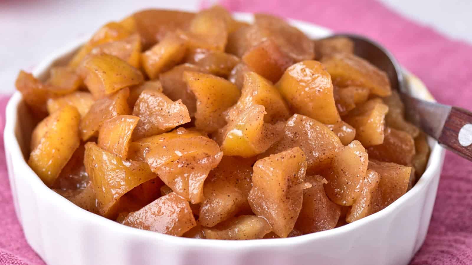 Cooked apples in a bowl, resting on a cozy pink towel.