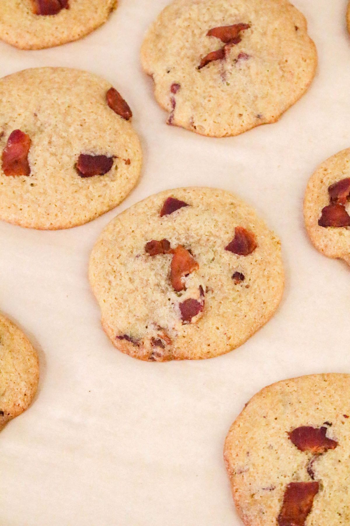 Cookies with chocolate chunks are arranged on parchment paper.