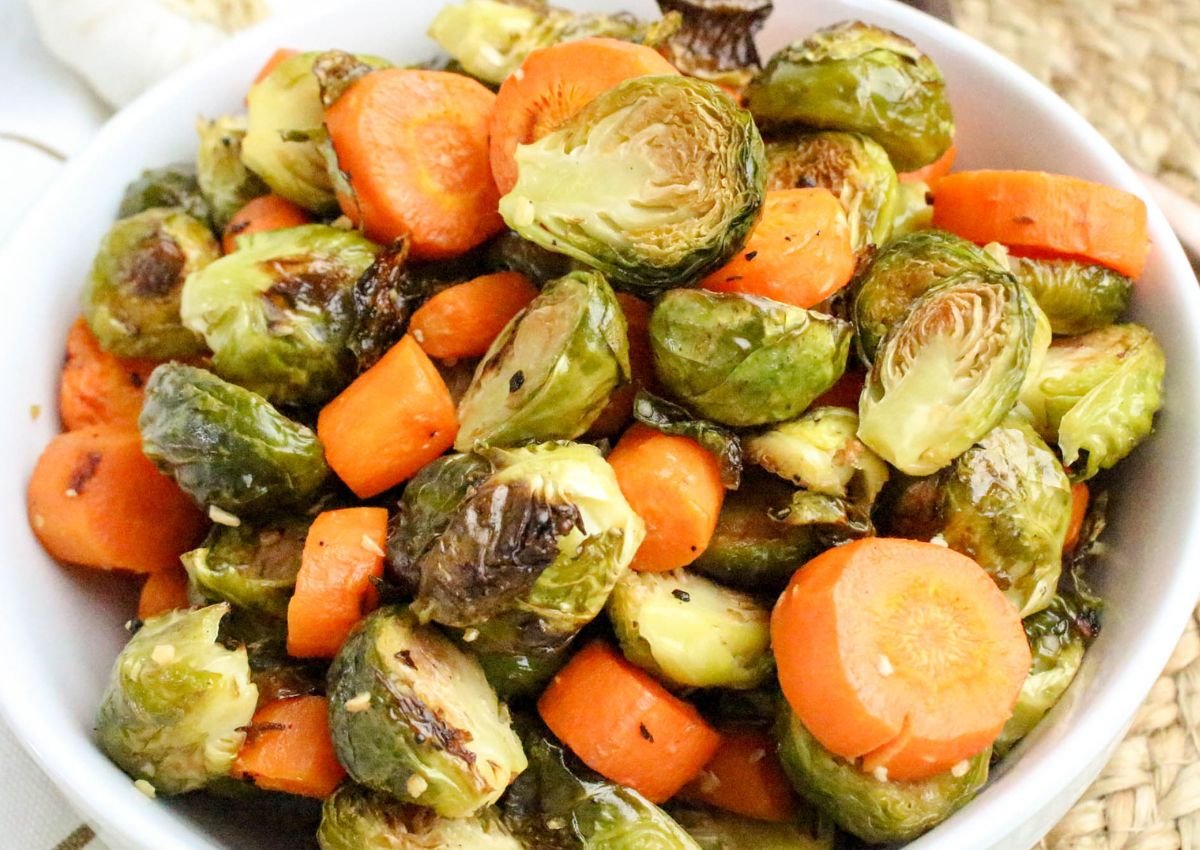 A bowl filled with roasted Brussels sprouts and sliced carrots.