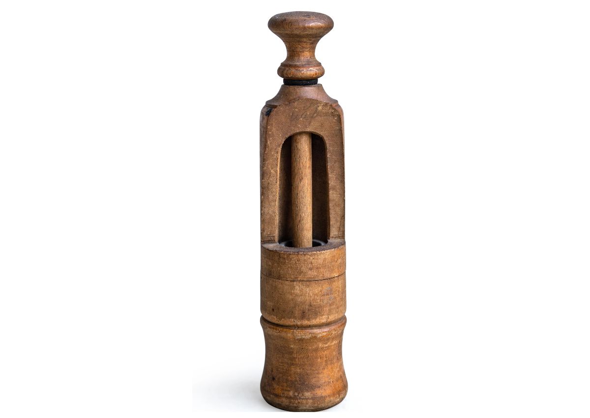 A vintage wooden butter churn with a handle and cylindrical base, featuring an open section showing the internal churning mechanism.