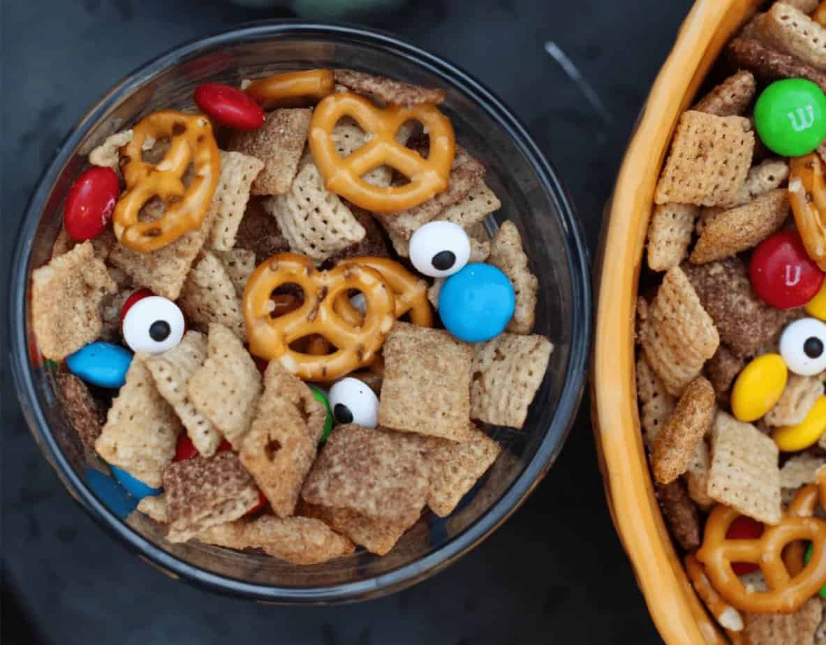 A bowl of snack mix containing Chex cereal, mini pretzels, candy-coated chocolates, and candy eyeballs.