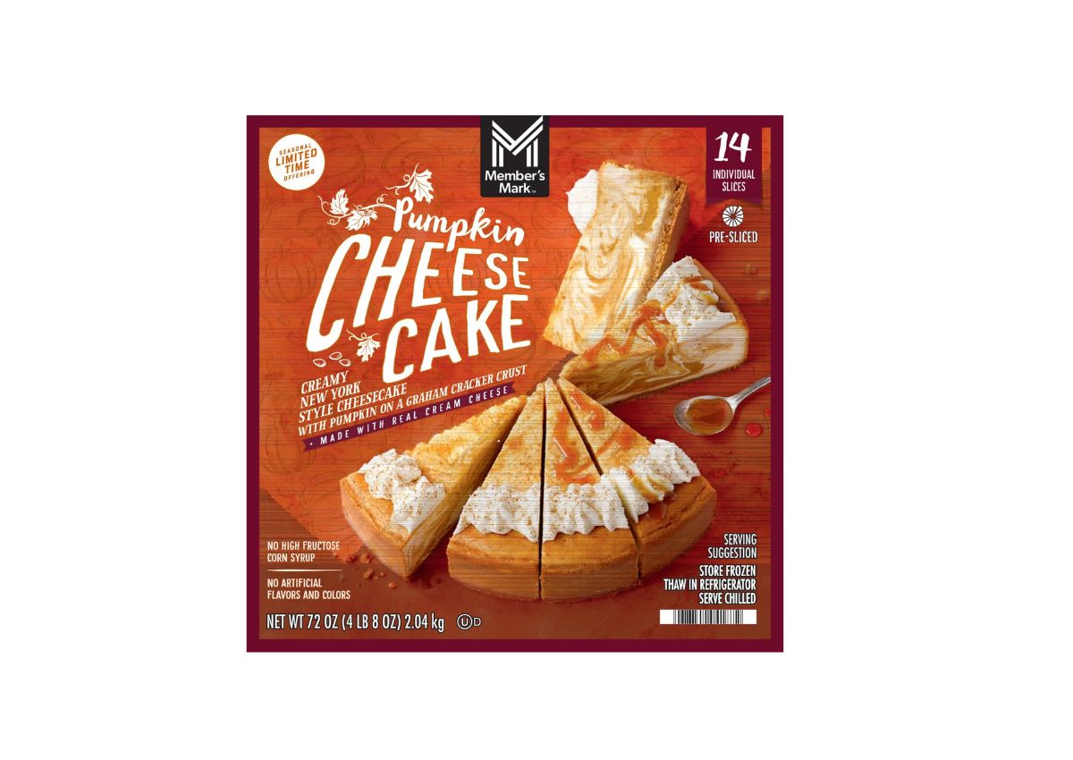 Members Mark Pumpkin Cheesecake box displaying a sliced cheesecake topped with pumpkin swirl. The box highlights it is pre-sliced with 14 servings and made with real cream cheese.