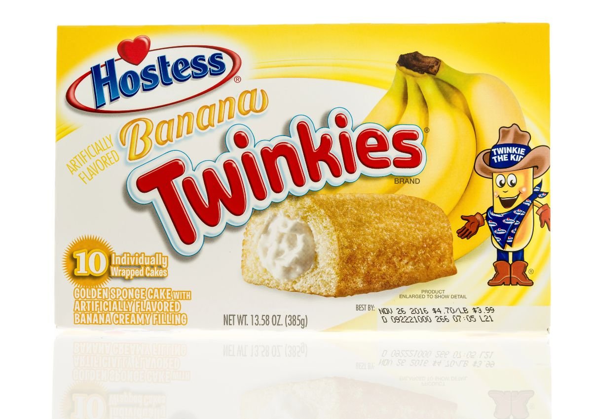 A box of Hostess Banana Twinkies featuring images of bananas, a Twinkie, packaging details, and a cartoon Twinkie mascot on a yellow background.