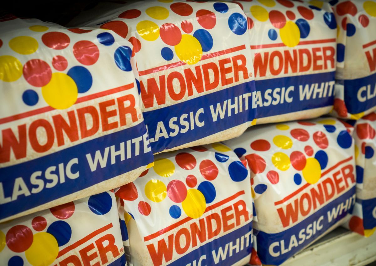 Several loaves of Wonder Classic White bread are stacked on a store shelf, with colorful polka dot packaging clearly visible.