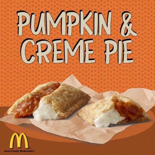 Two McDonalds pumpkin and creme pies with golden crusts, each split open to reveal pumpkin and white creme filling, are shown on brown parchment paper against an orange background.