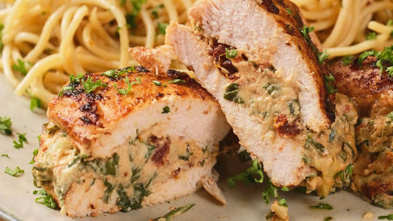 Sliced stuffed chicken breast filled with creamy spinach and cheese mixture, served with spaghetti in the background, garnished with chopped herbs.