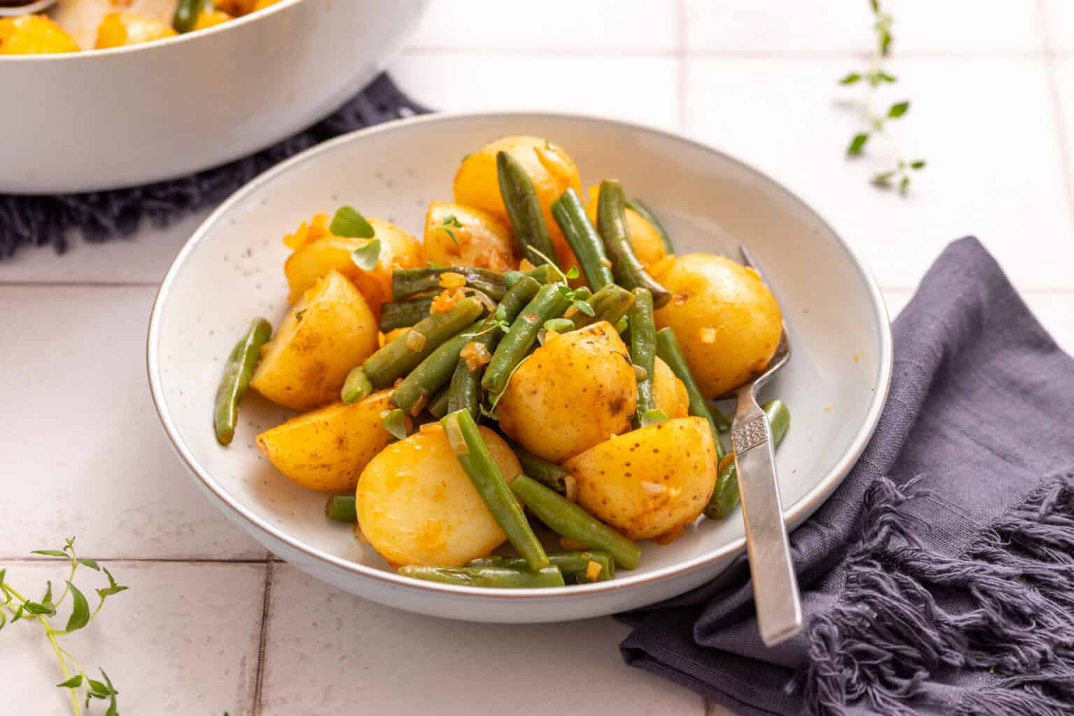 An image of green beans in a serving bowl with a spoon resting on it.