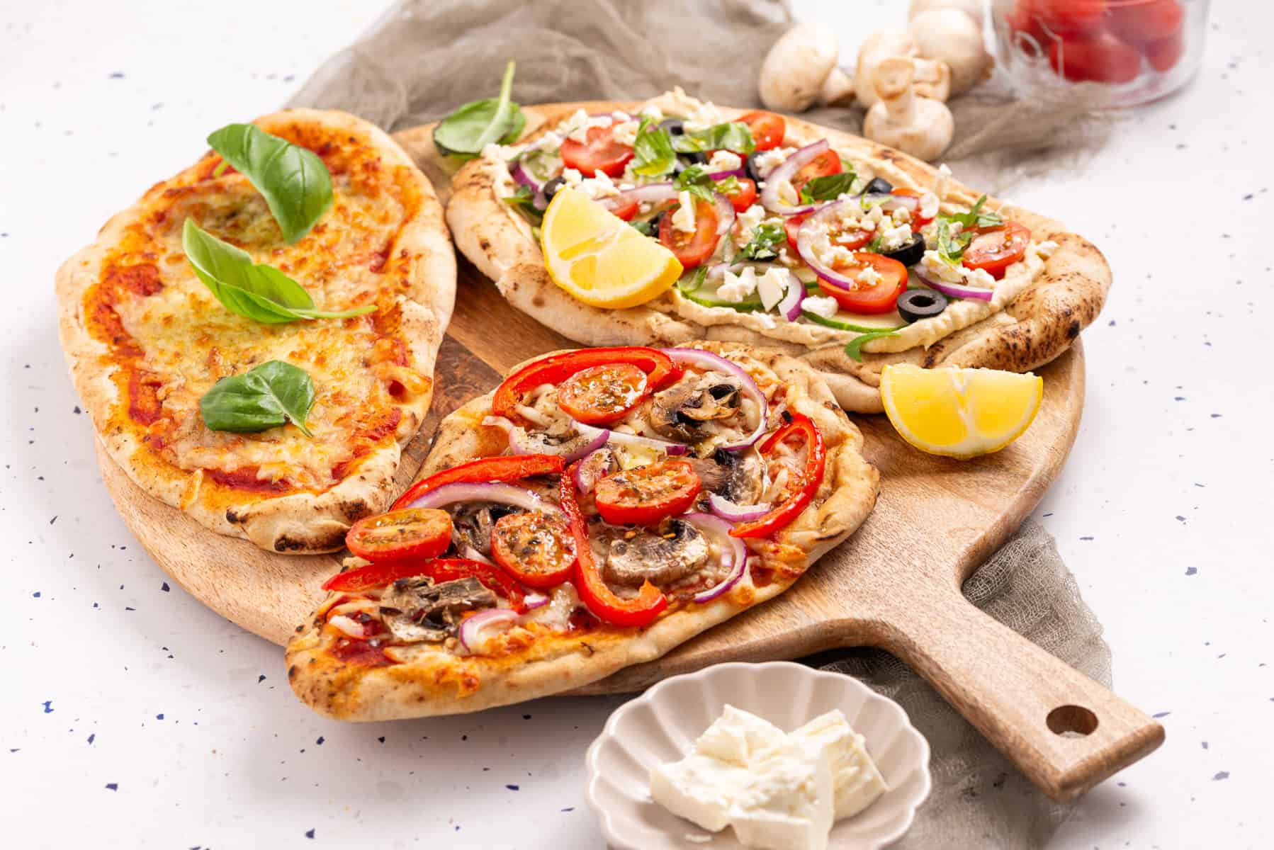 An image of naan pizza with different toppings on each.