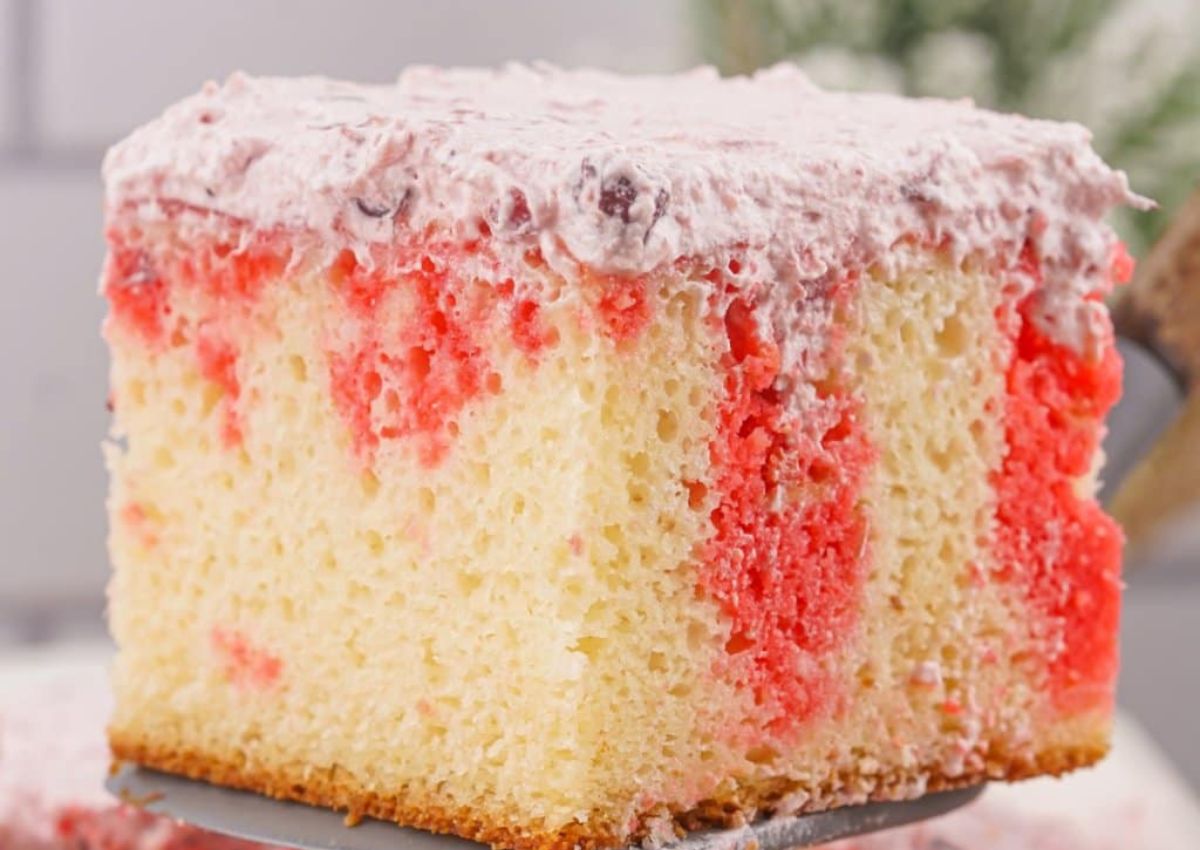 A slice of white cake with red gelatin streaks and topped with a layer of whipped cream frosting.