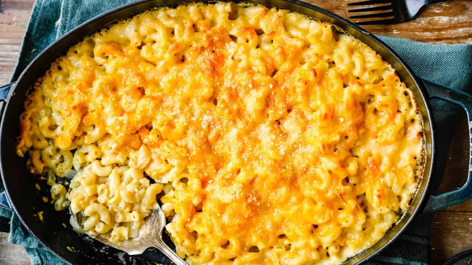 Baked macaroni and cheese in a casserole dish, with a portion scooped out, showing creamy pasta and a golden cheese topping.