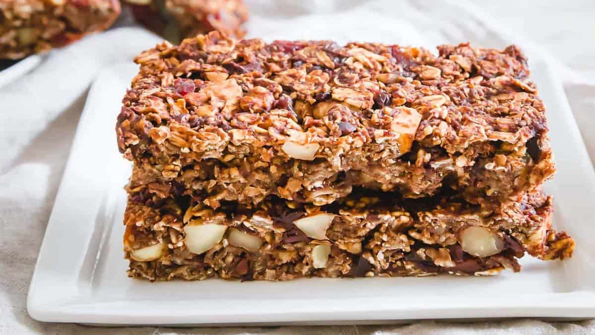Two rectangular granola bars with visible oats and nuts are stacked on a white plate.