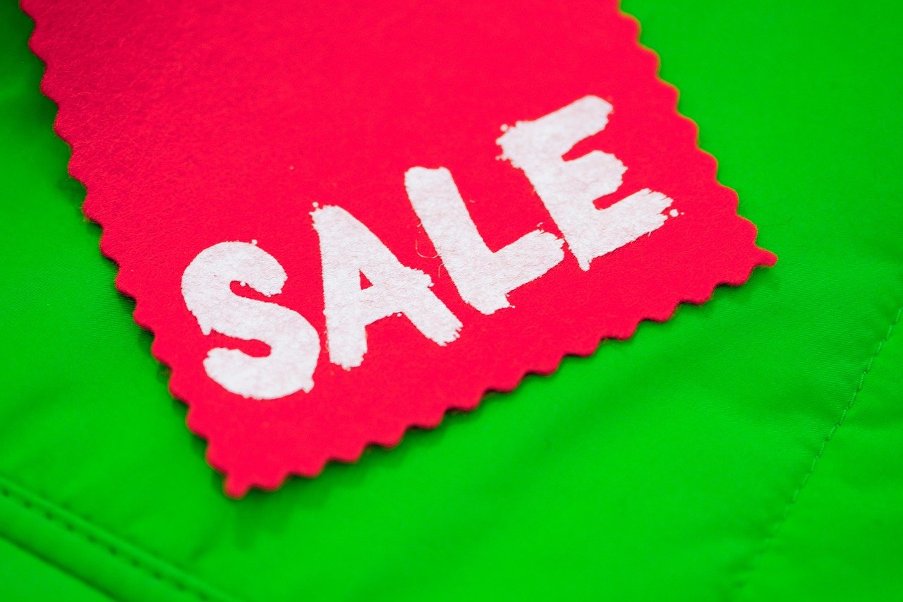 A red tag with the word SALE in white letters placed on a bright green background.
