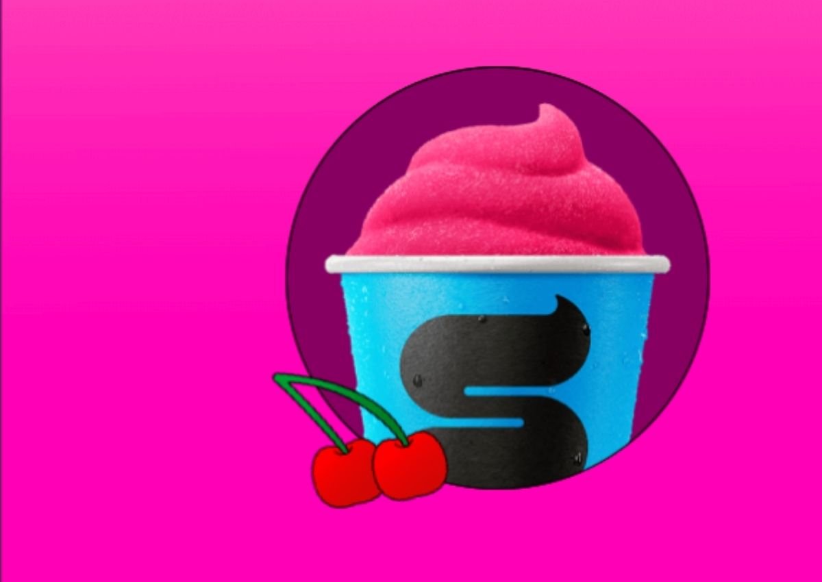 A blue cup filled with pink slush, featuring a large black S and two cartoon cherries in front, set against a pink background.