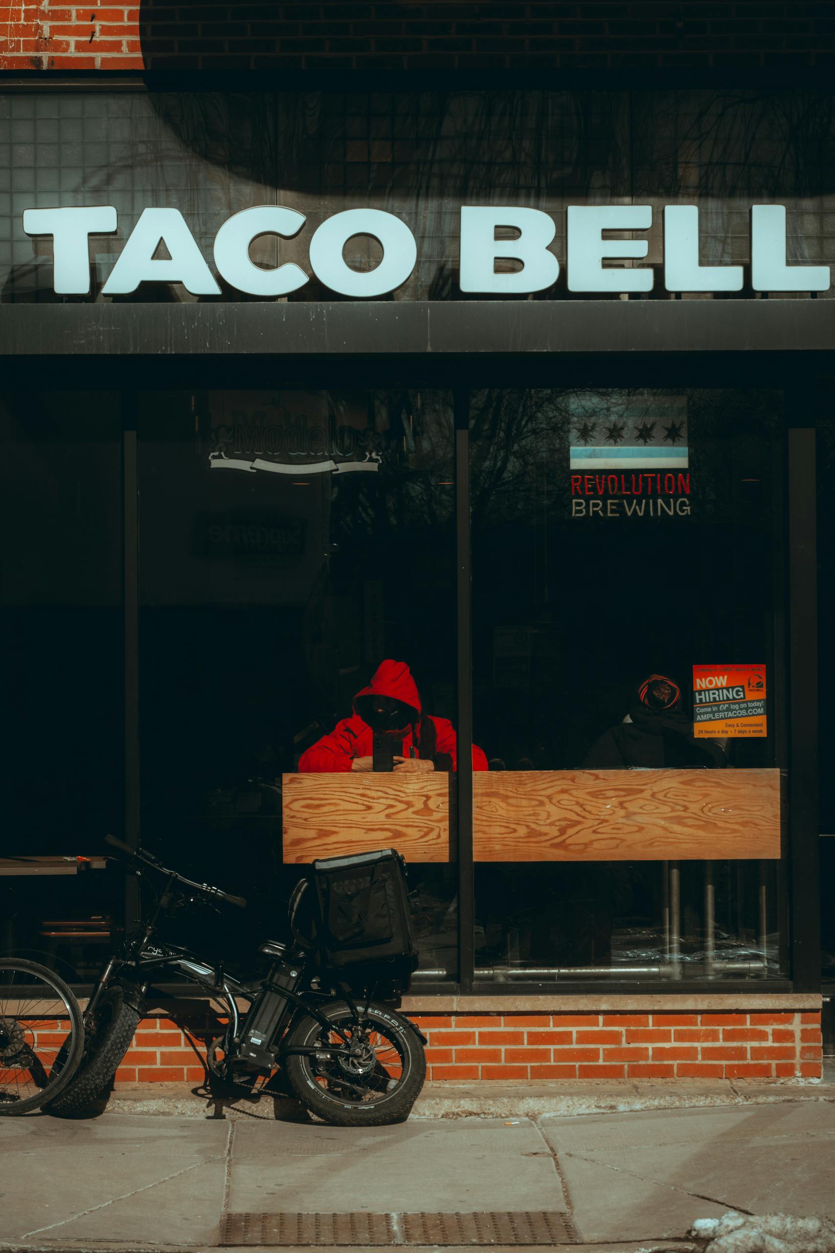 Taco Bell restaurant facade in urban Chicago with seated customers and a parked bicycle.
