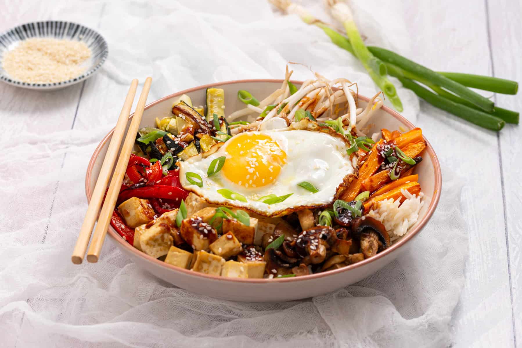 A bowl of Sheet Pan Bibimbap with a pair of chopsticks.