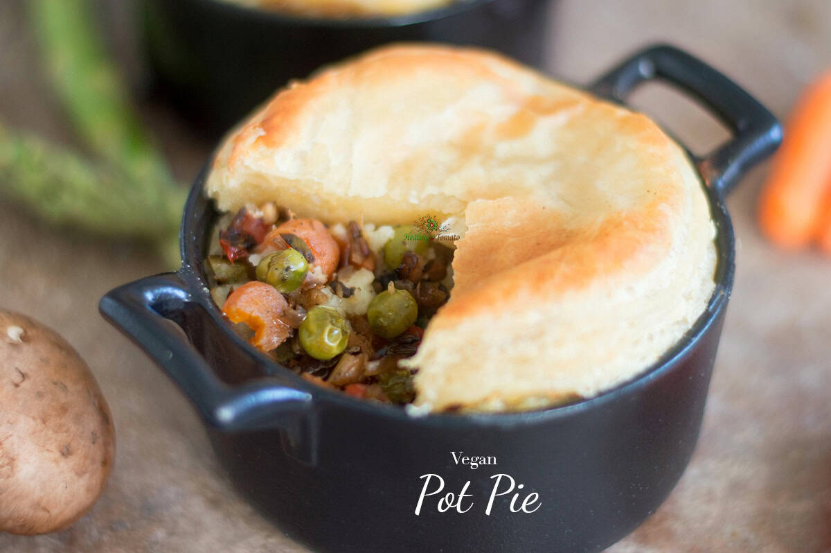 A small black pot filled with vegan pot pie, topped with golden crust and filled with vegetables like peas and carrots; “Vegan Pot Pie” text is overlaid at the bottom.