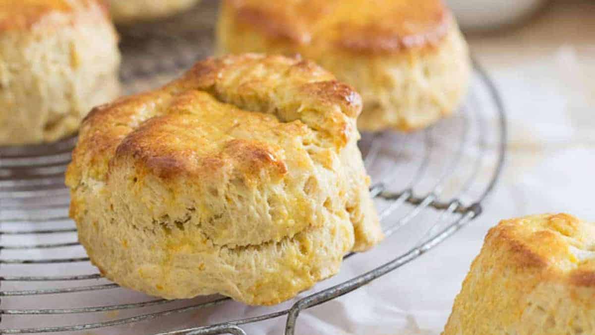 Freshly baked golden brown biscuits cooling on a metal wire rack.