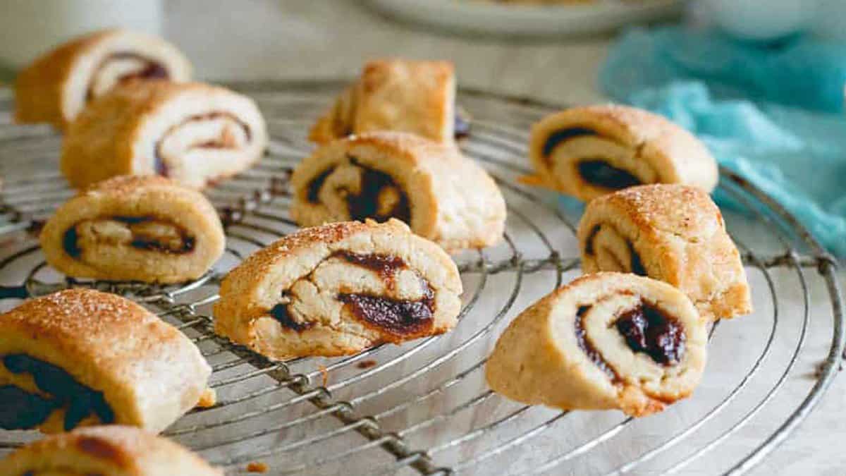 Sliced rugelach pastries with a dark filling are cooling on a round wire rack.
