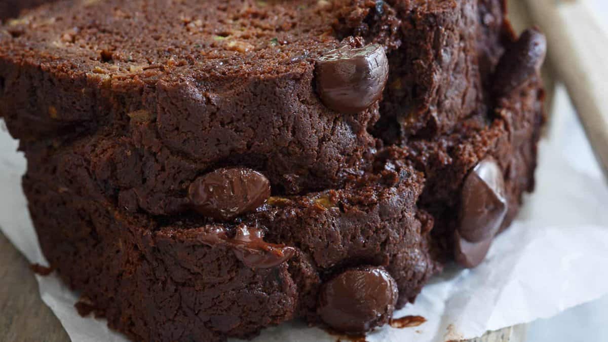 Close-up of two thick slices of chocolate bread with visible melted chocolate chips, resting on a piece of parchment paper.