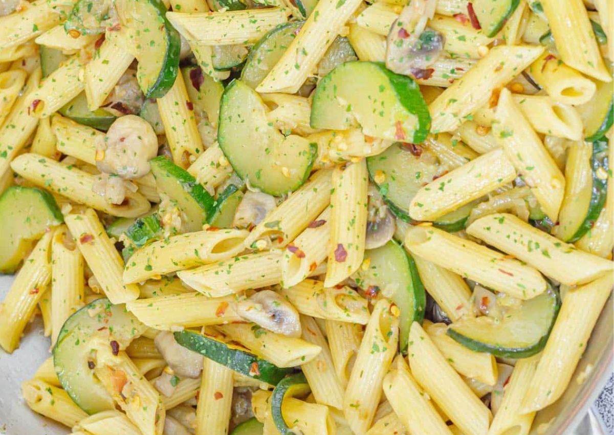 Penne pasta mixed with sliced zucchini, mushrooms, and herbs, topped with red pepper flakes.
