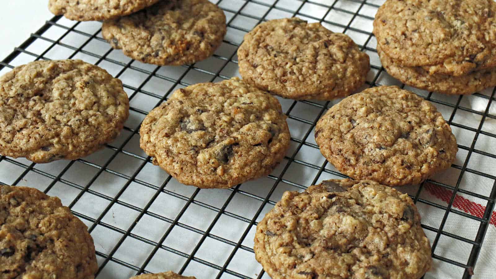 Oatmeal cookies cooling on a black wire rack placed over a white surface.