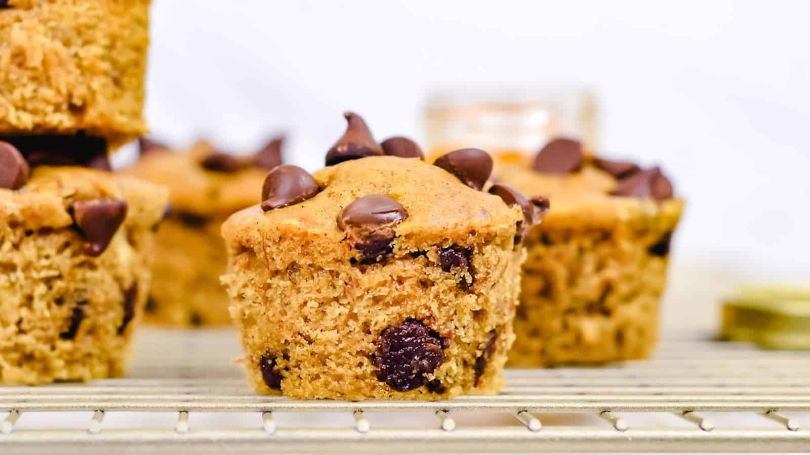 Close-up of chocolate chip muffins on a cooling rack, with chocolate chips visible on top and inside the muffins.
