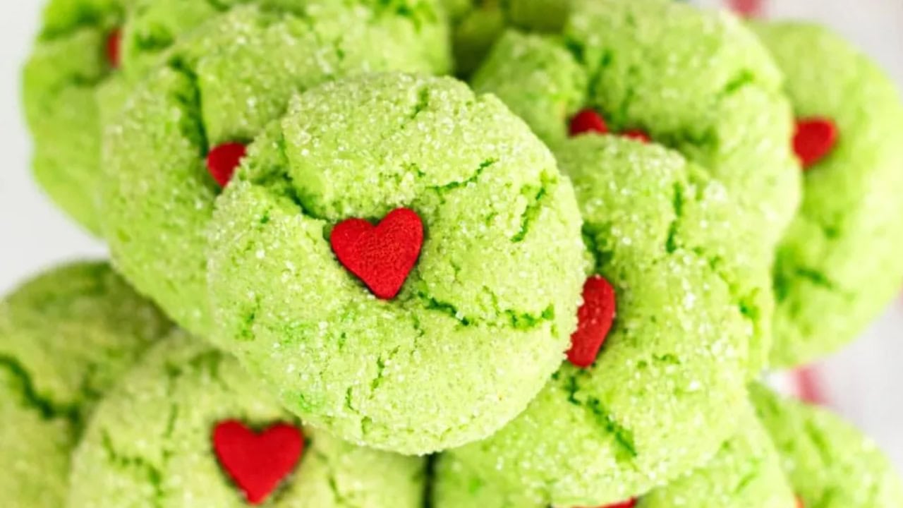 A close-up of green sugar cookies topped with small red heart-shaped decorations.