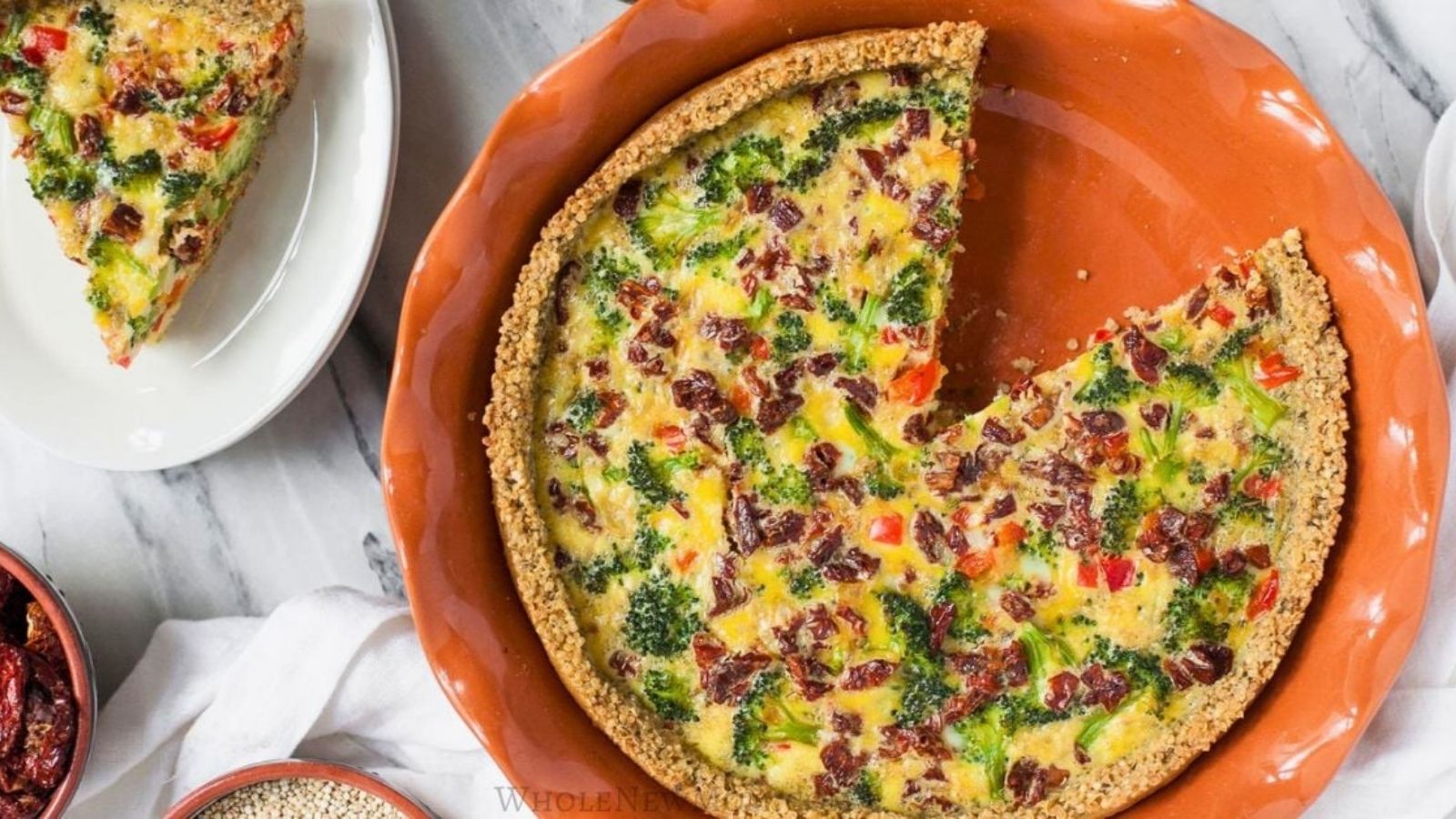 A baked vegetable quiche with a slice removed, showing a filling of broccoli, red peppers, and bits of bacon in a pie crust, presented in an orange dish.
