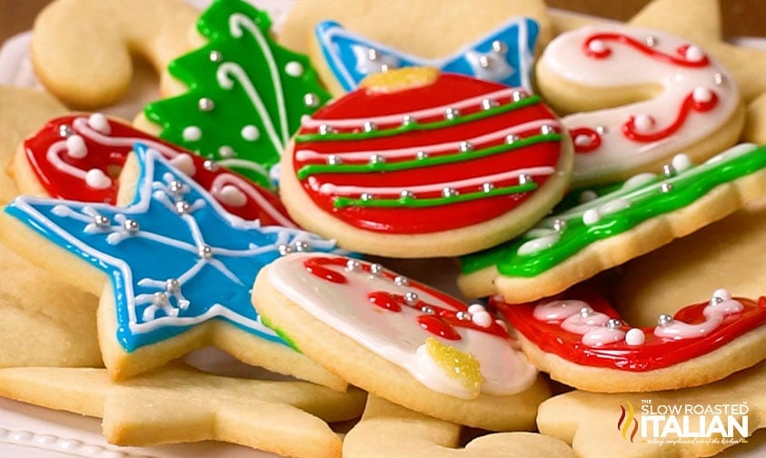 A plate of assorted Christmas sugar cookies decorated with colorful icing in shapes like stars, ornaments, and trees.