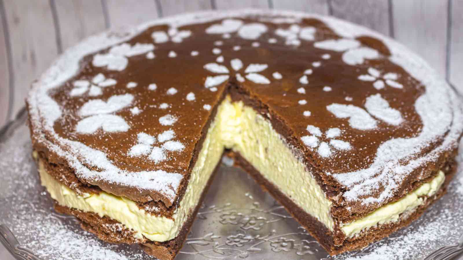 Chocolate cake with a thick cream filling, decorated with powdered sugar patterns of butterflies and flowers, with one slice removed.