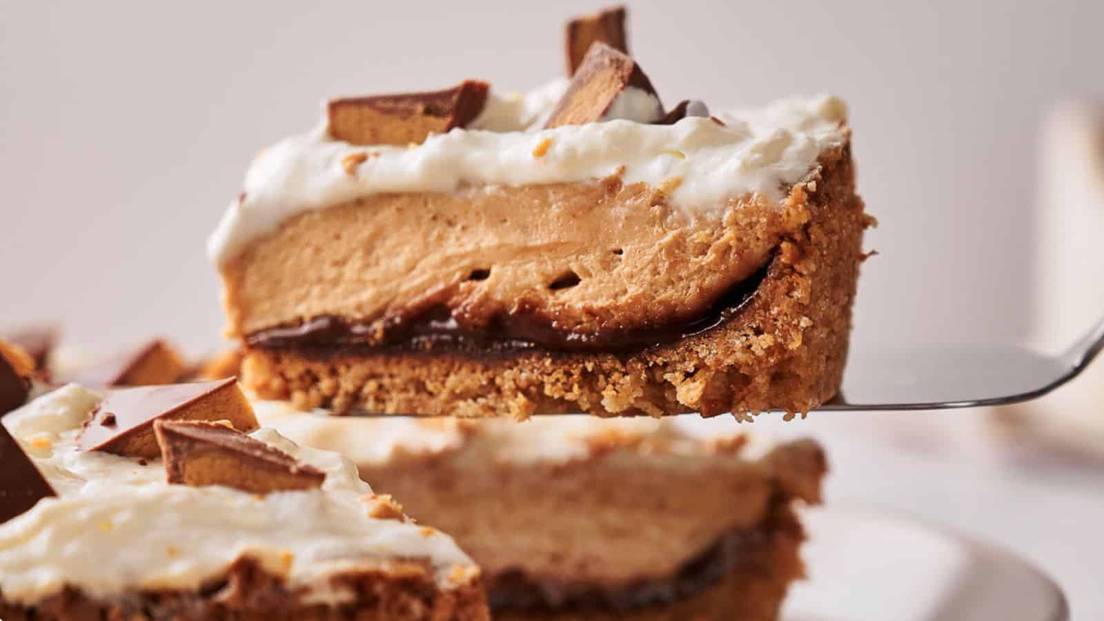 A slice of pie with a crumbly crust, chocolate layer, peanut butter filling, whipped topping, and chopped chocolate pieces on top.