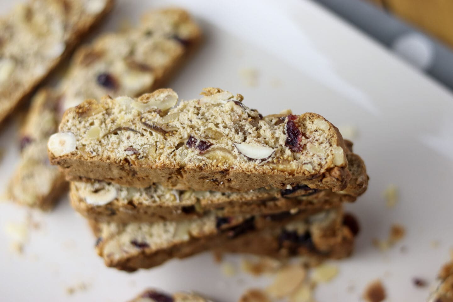 A close-up of several almond and cranberry biscotti stacked on a white plate.