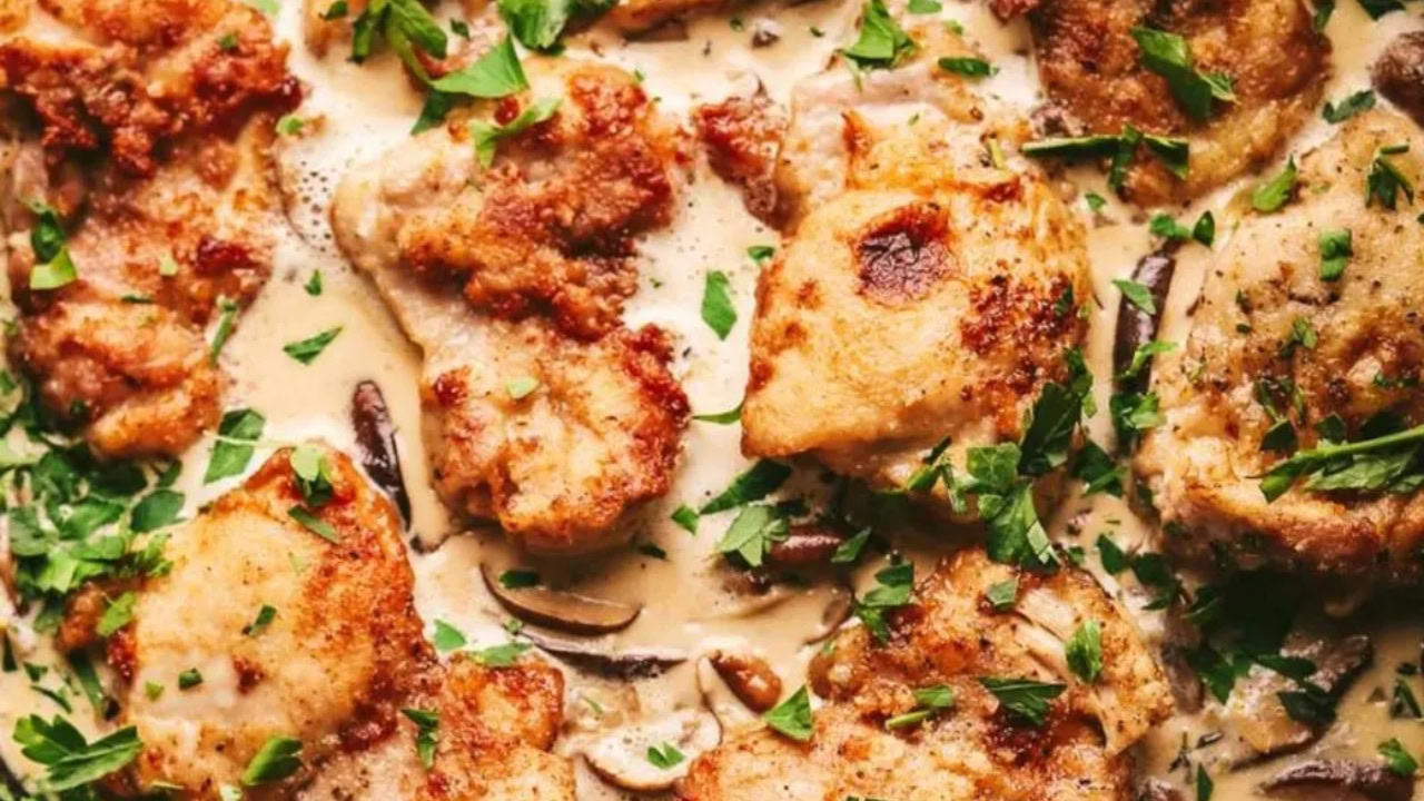 Crispy chicken pieces in a creamy sauce with mushrooms, garnished with chopped parsley.